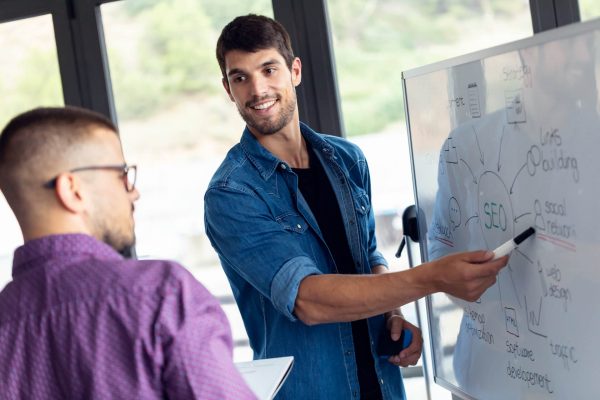 business-young-man-pointing-on-whiteboard-while-di-2022-12-15-18-19-03-utc